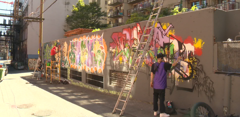 Street artists drawing on Vancouver’s first legal graffiti wall